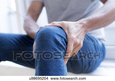 Man holding his left knee in pain. View Large Photo Image Picture - Man holding his left knee in pain.. Fotosearch