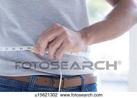 Stock Image - Man measuring waist.. Fotosearch