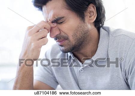 Stock Photograph - Man pinching the bridge of his nose.. Fotosearch