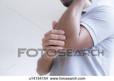 Picture - Man touching his elbow in pain.. Fotosearch