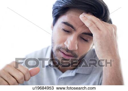 Stock Image - Man touching his forehead in pain.. Fotosearch