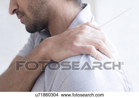 Picture - Man touching his shoulder in pain.. Fotosearch