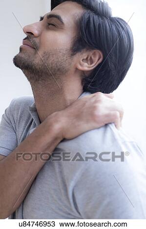 Stock Image - Man touching his shoulder in pain.. Fotosearch