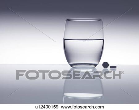 Stock Photo - Tablets next to a glass of water.. Fotosearch