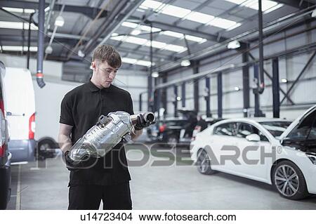 Apprentice holding catalytic converter in car service centre View Large Photo Image Picture - Apprentice holding catalytic converter in car service centre. Fotosearch