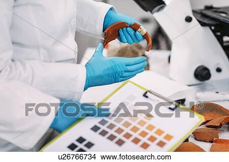 Picture - Archaeologist comparing pottery colours. Fotosearch