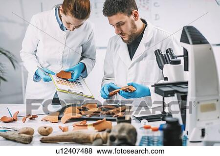 Stock Photo - Archaeologist comparing pottery colours. Fotosearch
