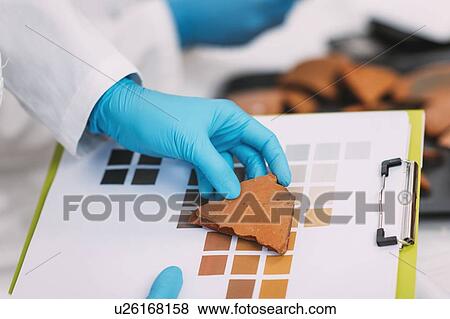 Stock Photo - Archaeologist comparing pottery colours. Fotosearch