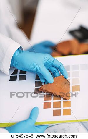Stock Photograph - Archaeologist comparing pottery colours. Fotosearch