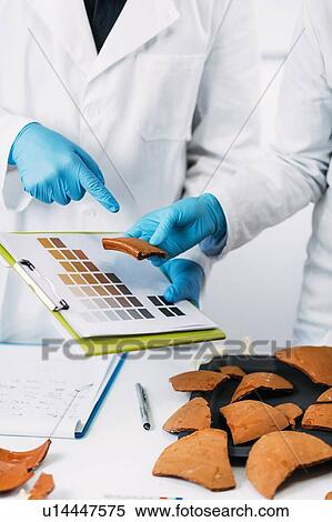 Stock Photography - Archaeologist comparing pottery colours. Fotosearch