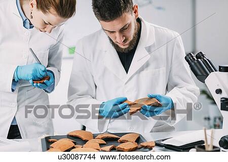 Picture - Archaeologists reconstructing broken pottery. Fotosearch