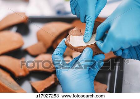 Stock Image - Archaeologists reconstructing broken pottery. Fotosearch