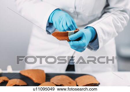 Stock Photo - Archaeologists reconstructing broken pottery. Fotosearch