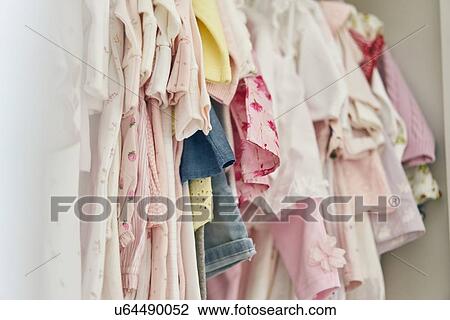 Stock Image - Assortment of baby clothing hung inside cupboard. Fotosearch
