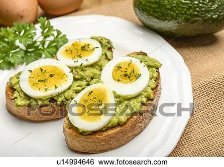 Stock Photograph - Avocado and egg on toast with parsley. Fotosearch
