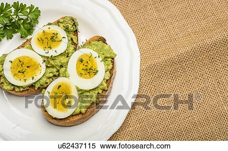 Stock Photography - Avocado and egg on toast with parsley. Fotosearch