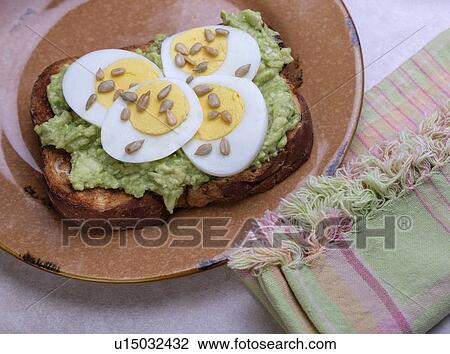 Stock Image - Avocado and egg on toast with sunflower seeds. Fotosearch
