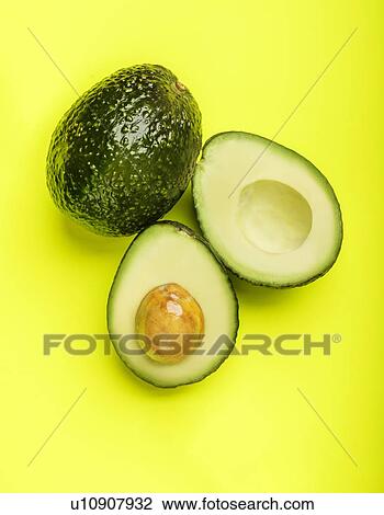 Stock Image - Avocados on green surface. Fotosearch