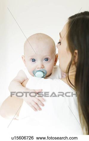 Baby boy using pacifier looking over his mother's shoulder View Large Photo Image Stock Photograph - Baby boy using pacifier looking over his mother's shoulder. Fotosearch