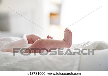 Stock Image - Baby lying down on U-shaped pillow at home. Fotosearch