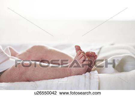 Stock Image - Baby lying down on U-shaped pillow at home. Fotosearch