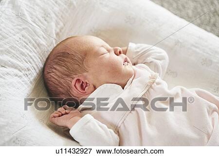 Stock Photo - Baby sleeping on U-shaped pillow at home. Fotosearch