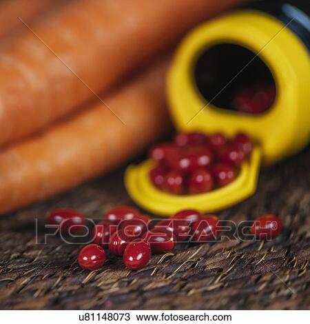 Stock Image - Beta carotene supplement pills and vegetables. Fotosearch