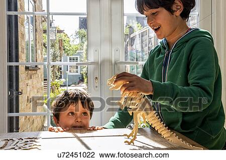 Boy and little brother playing with wooden dinosaur View Large Photo Image Stock Image - Boy and little brother playing with wooden dinosaur. Fotosearch