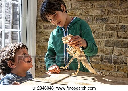 Boy and little brother playing with wooden dinosaur View Large Photo Image Stock Photo - Boy and little brother playing with wooden dinosaur. Fotosearch