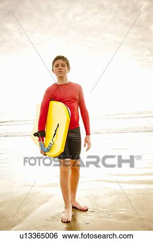 Boy holding body board on beach View Large Photo Image Stock Photograph - Boy holding body board on beach. Fotosearch