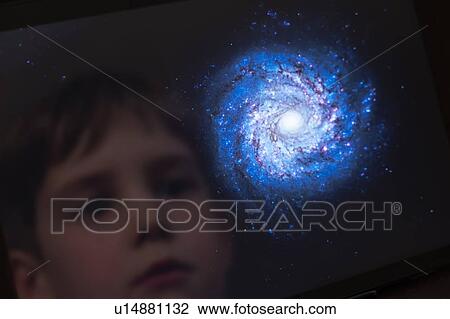 Stock Image - Boy looking at a galaxy. Fotosearch