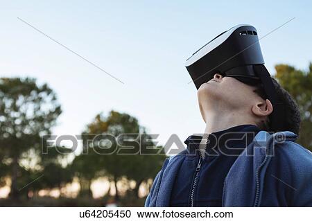 Stock Image - Boy wearing virtual reality simulator outdoors. Fotosearch