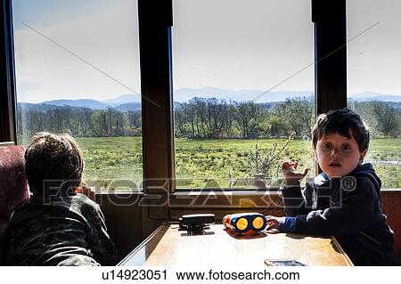 Stock Image - Boys travelling in train passing national park, Llanaber, Gwynedd, United Kingdom. Fotosearch
