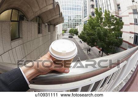 Stock Image - Businessman holding disposable coffee cup. Fotosearch
