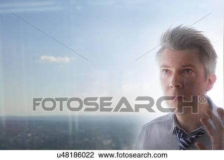 Stock Image - Businessman looking through window. Fotosearch