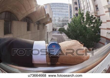 Stock Photo - Businessman taking his pulse on a smartwatch. Fotosearch