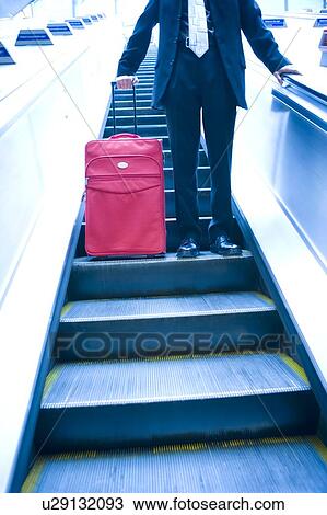 Stock Image - Businessman travelling down an escalator. Fotosearch