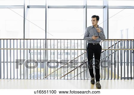 Businessman using smartphone in office corridor View Large Photo Image Stock Image - Businessman using smartphone in office corridor. Fotosearch