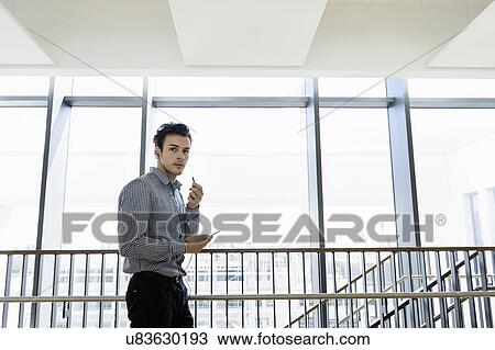 Businessman using smartphone in office corridor View Large Photo Image Stock Image - Businessman using smartphone in office corridor. Fotosearch