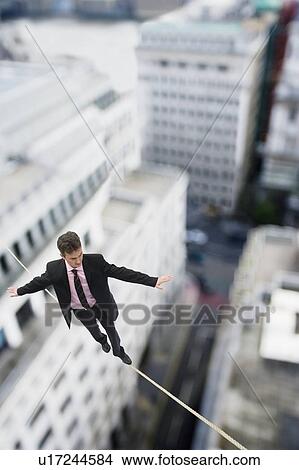 Businessman walking on a tightrope View Large Photo Image Picture - Businessman walking on a tightrope. Fotosearch