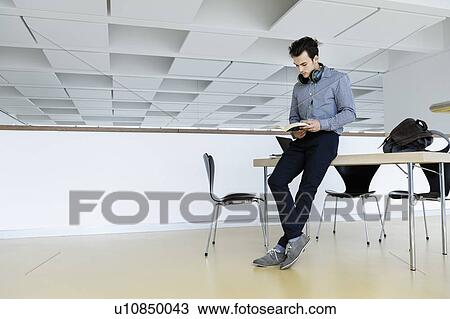 Businessman with headphones reading book in office View Large Photo Image Stock Image - Businessman with headphones reading book in office. Fotosearch
