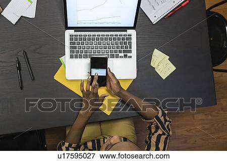 Businesswoman analysing work using laptop and cellphone View Large Photo Image Stock Photo - Businesswoman analysing work using laptop and cellphone. Fotosearch