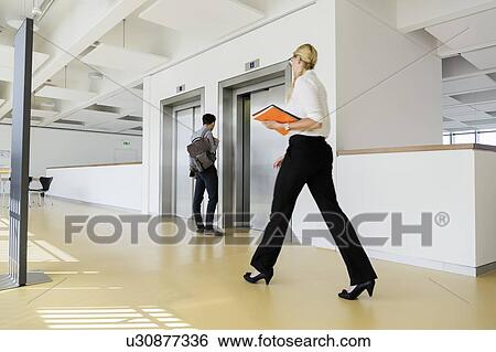 Businesswoman and businessman in office corridor View Large Photo Image Stock Photograph - Businesswoman and businessman in office corridor. Fotosearch
