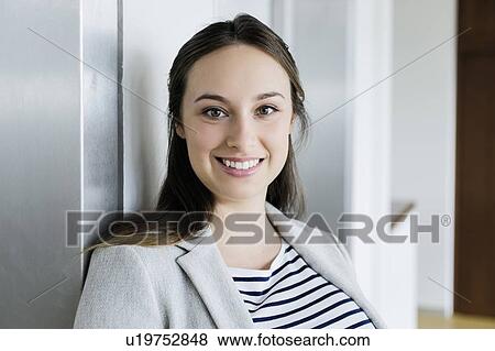 Stock Photo - Businesswoman leaning against elevator door. Fotosearch