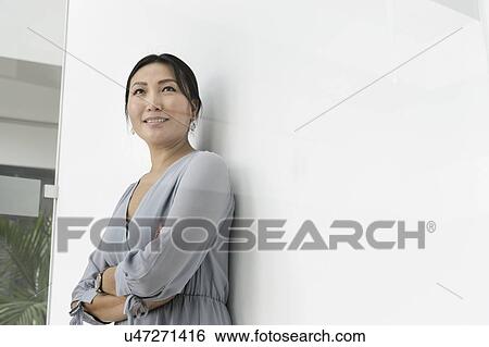 Businesswoman leaning against white wall in office View Large Photo Image Stock Photograph - Businesswoman leaning against white wall in office. Fotosearch