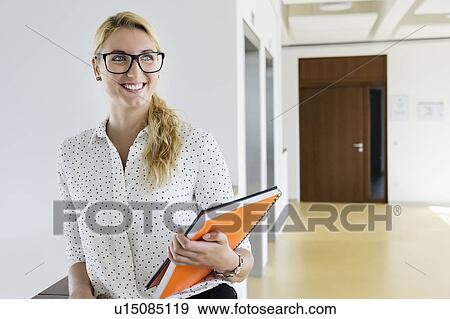 Businesswoman taking break in office corridor View Large Photo Image Stock Photo - Businesswoman taking break in office corridor. Fotosearch