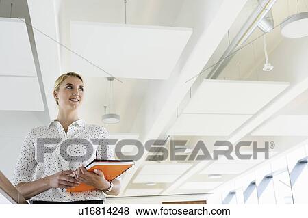 Businesswoman taking break in office corridor View Large Photo Image Stock Photo - Businesswoman taking break in office corridor. Fotosearch