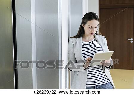 Businesswoman using digital tablet beside elevator View Large Photo Image Stock Image - Businesswoman using digital tablet beside elevator. Fotosearch