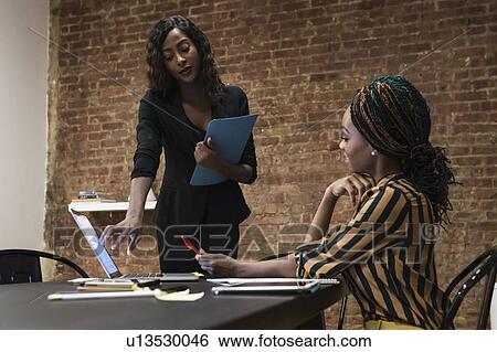 Stock Photograph - Businesswomen analysing work using laptop. Fotosearch