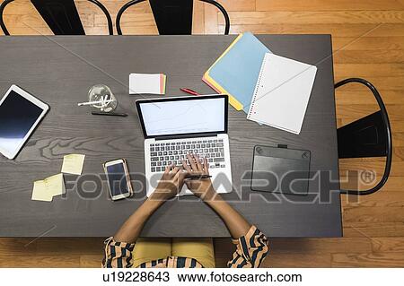 Stock Image - Businesswomen using digital tablet, laptop and cellphone on desk. Fotosearch
